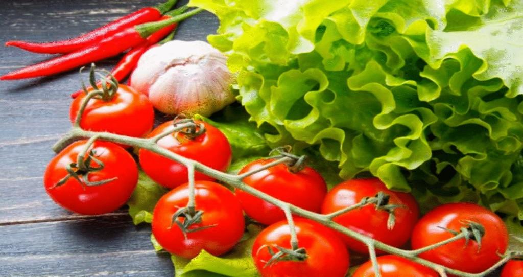 Fresh tomatoes on the vine with lettuce, garlic, and red chili peppers